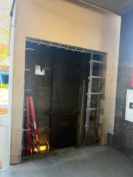 Wall-sawed elevator shaft opening revealing exposed reinforcement rebar along top and sides