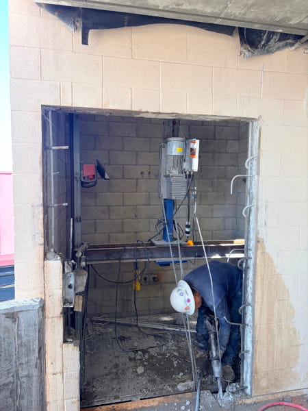 Faast Forward Concrete Cutting worker modifying the freshly sawed edges of a concrete elevator shaft opening