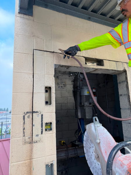 Fast Forward Concrete Cutting worker preparing a concrete wall for wall sawing modifications near an elevator opening