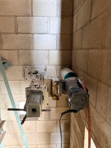 Wall-mounted concrete core drill setup against a masonry block wall