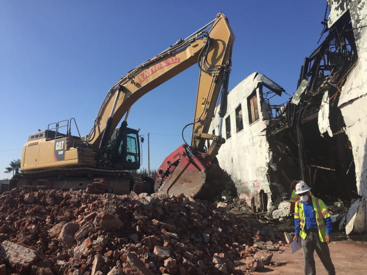 excavator demolishing buildng with heavy-duty clamshell bucket
