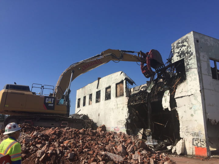 excavator demolishing buildng with heavy-duty clamshell bucket