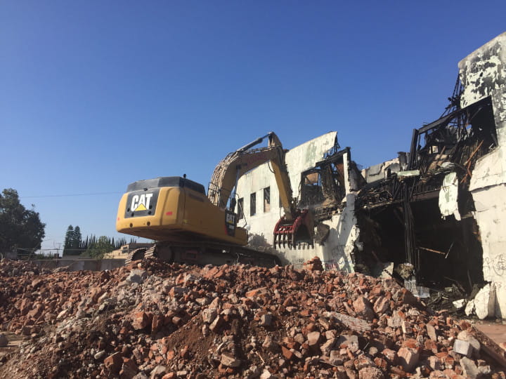 excavator demolishing buildng with heavy-duty clamshell bucket