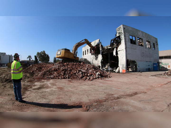 excavator demolishing buildng with heavy-duty clamshell bucket